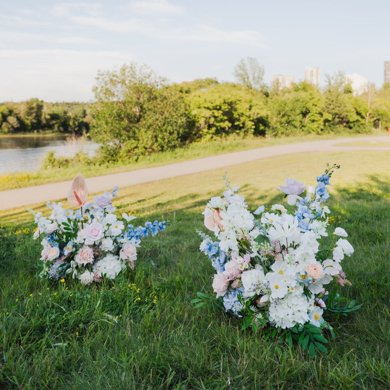 Pair of pastel faux floor florals with roses, hydrangeas, and greenery, styled outdoors for wedding aisle markers or reception floral rentals in Edmonton.