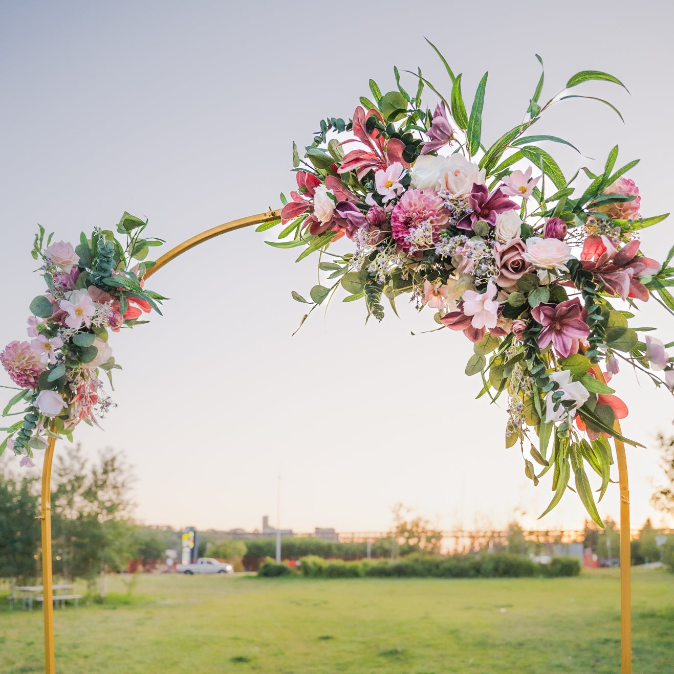 Floral archway in a grassy field with a clear sky