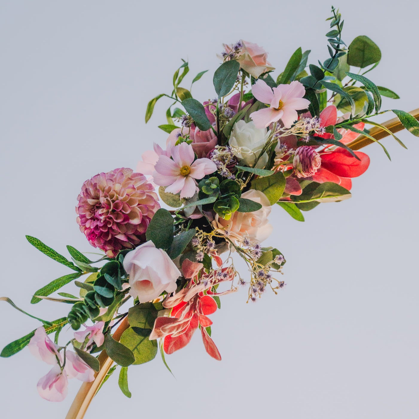 Floral arrangement with pink, red, and white flowers on a light blue background