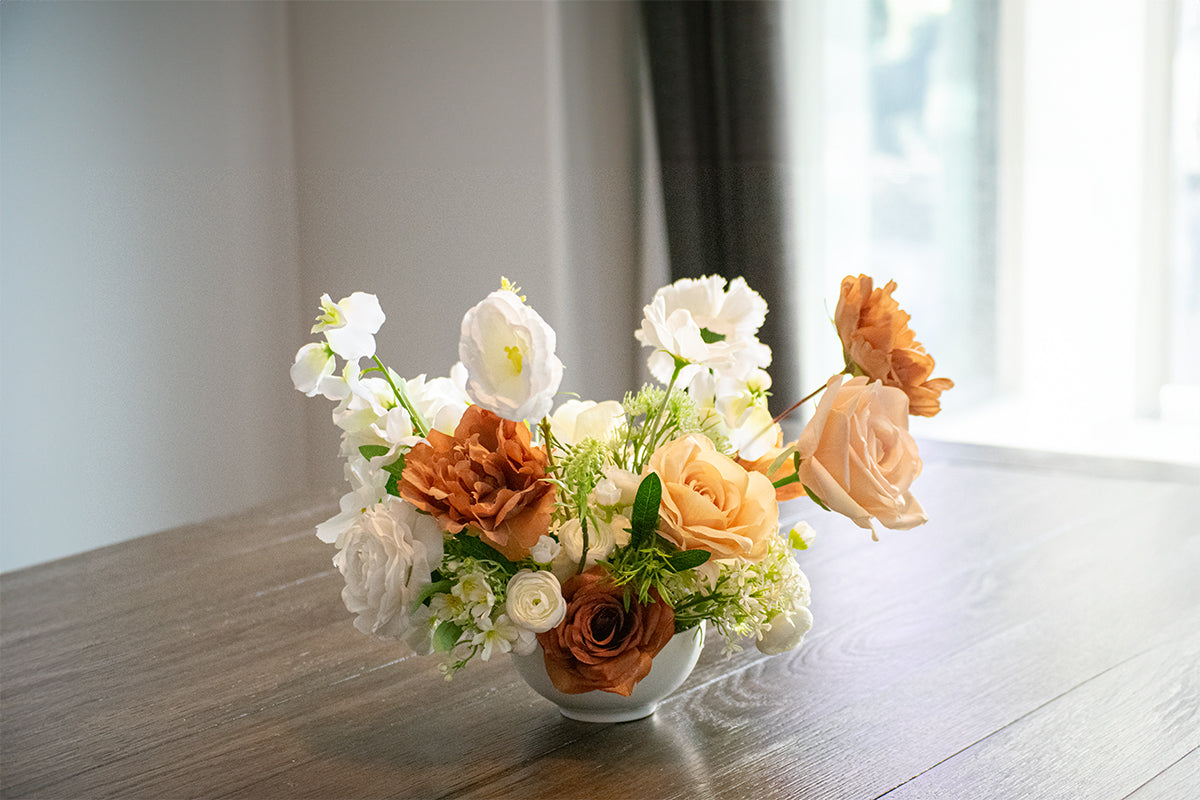 Faux flower centrepiece on a wooden table with a blurred background