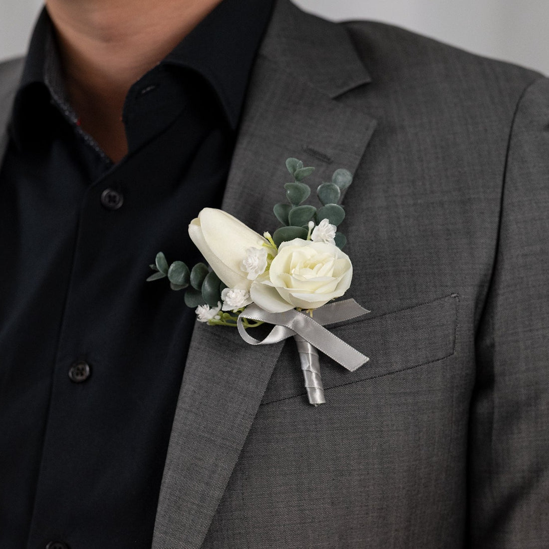 The elegant &quot;White Harmony Boutonniere&quot; features a stunning white rose and tulip, ensuring an unforgettable look. Perfect for weddings, celebrations, or formal events, its white composition adds a sleek touch of grace and class to any occasion.