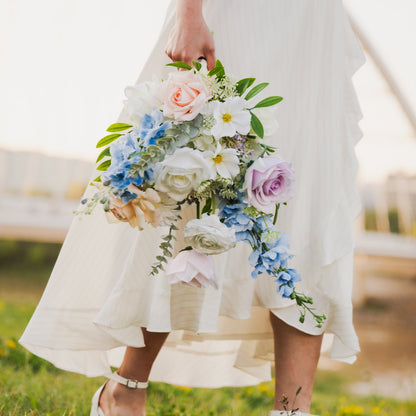 Person in a white dress holding a real touch, faux flower bouquet in a grassy field (Edmonton, AB).