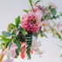 Arch floral arrangement with pink flowers and green leaves on a light background