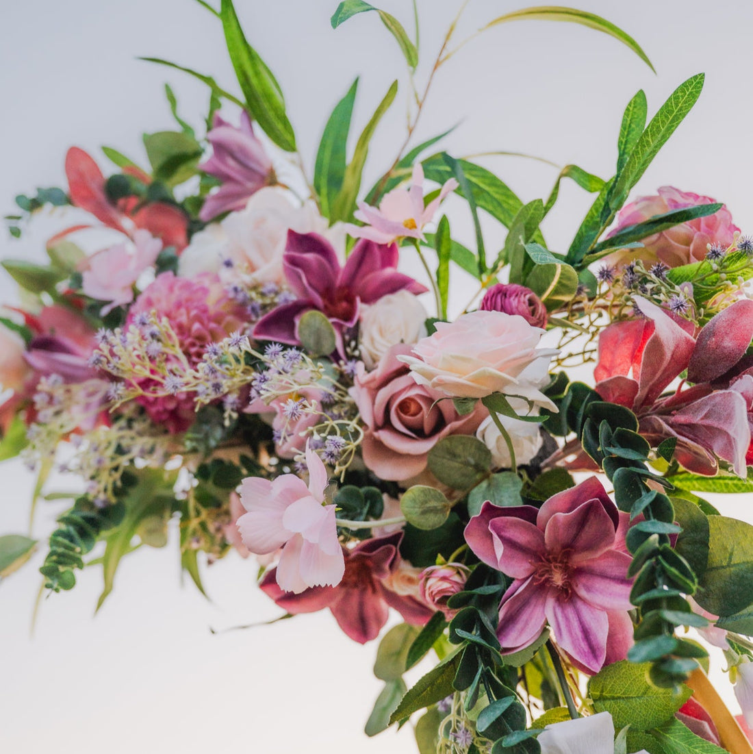 Floral arch with pink, white, and green flowers against a blurred outdoor background