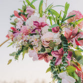 Floral arch with pink and white flowers against a blurred natural background