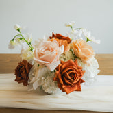 Close-up of Cocoa Bloom artificial floral arrangement with caramel, ivory, and copper roses, set in a white bowl vase on a neutral table runner.
