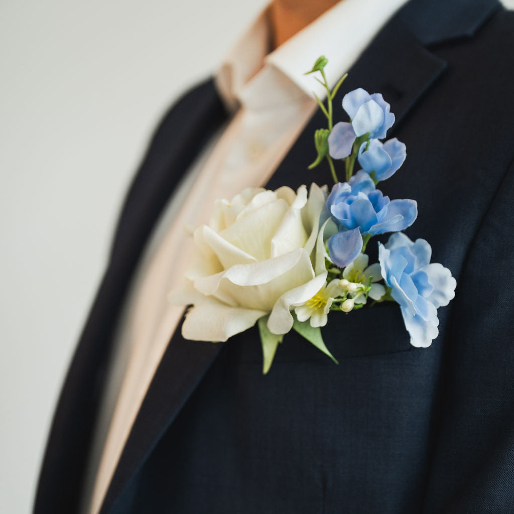 Ocean Breeze groom boutonniere on a dark suit jacket with a plain background