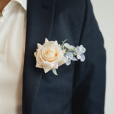 Navy suit jacket with a white rose boutonniere on a neutral background