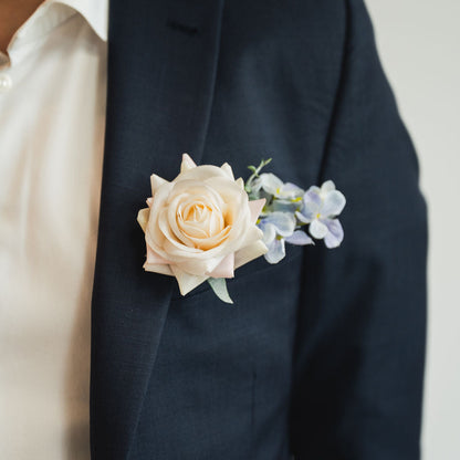 Navy suit jacket with a white rose boutonniere on a neutral background