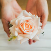 Hands holding artificial pastel rose corsage, real-touch faux flowers for Edmonton wedding corsage rentals.
