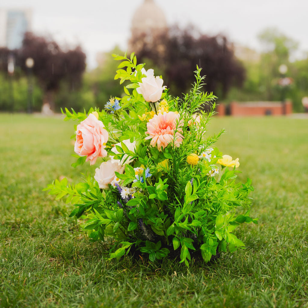 Close up of Wildest Dreams floor floral arrangements on grass with a blurred background near the Alberta Legislature building in Edmonton, Alberta.