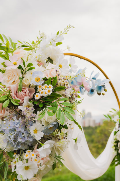 Artificial wedding flowers on a rental arch in Edmonton, with a mix of faux blush roses, ivory roses, silk hydrangeas, daisies, and greenery for a romantic look.