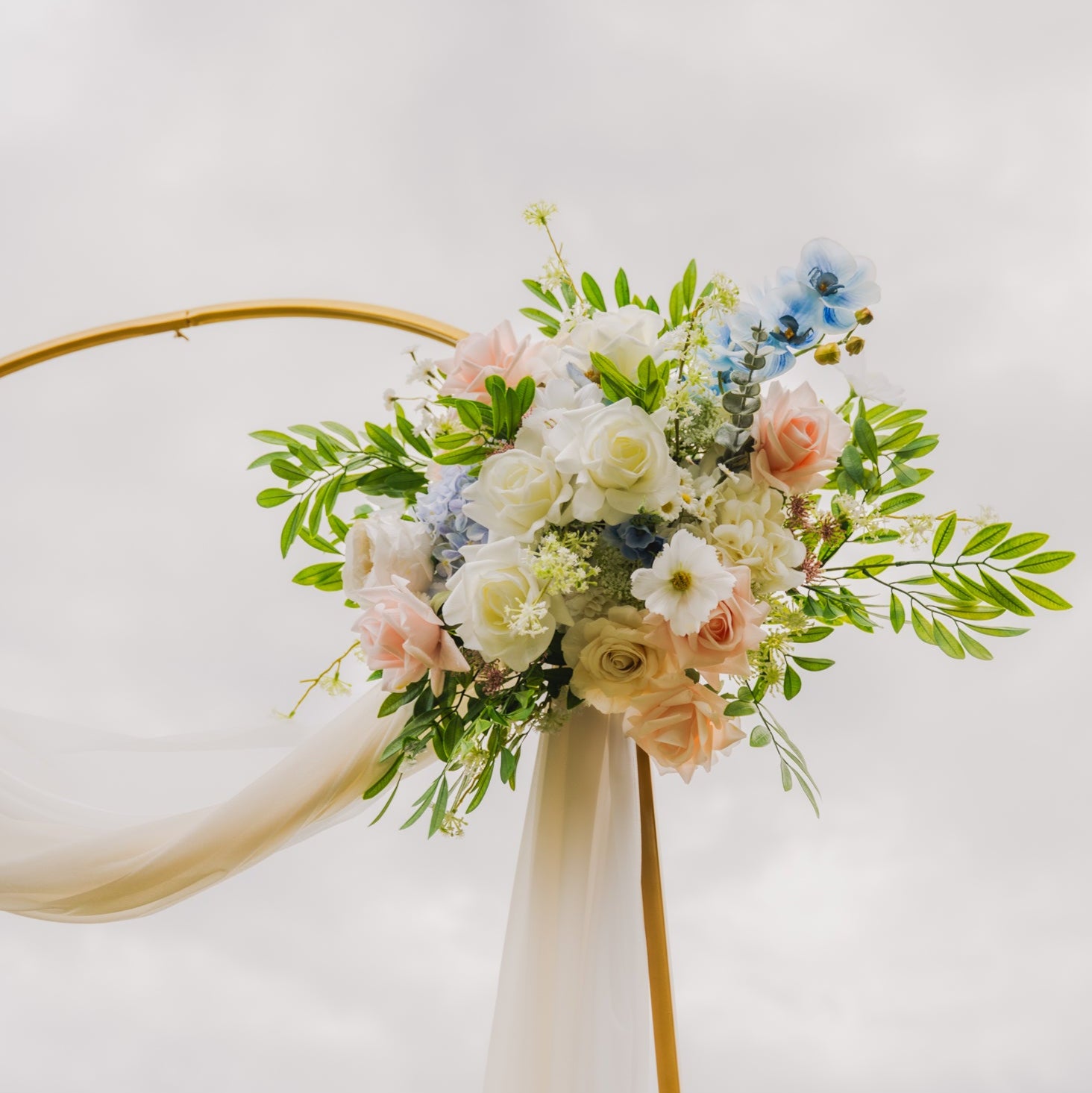 Close-up of faux pastel floral wedding arch arrangement with real touch blue orchids, blush roses, ivory roses, and greenery, available as an Edmonton floral arch rental for ceremonies and receptions (weddings).