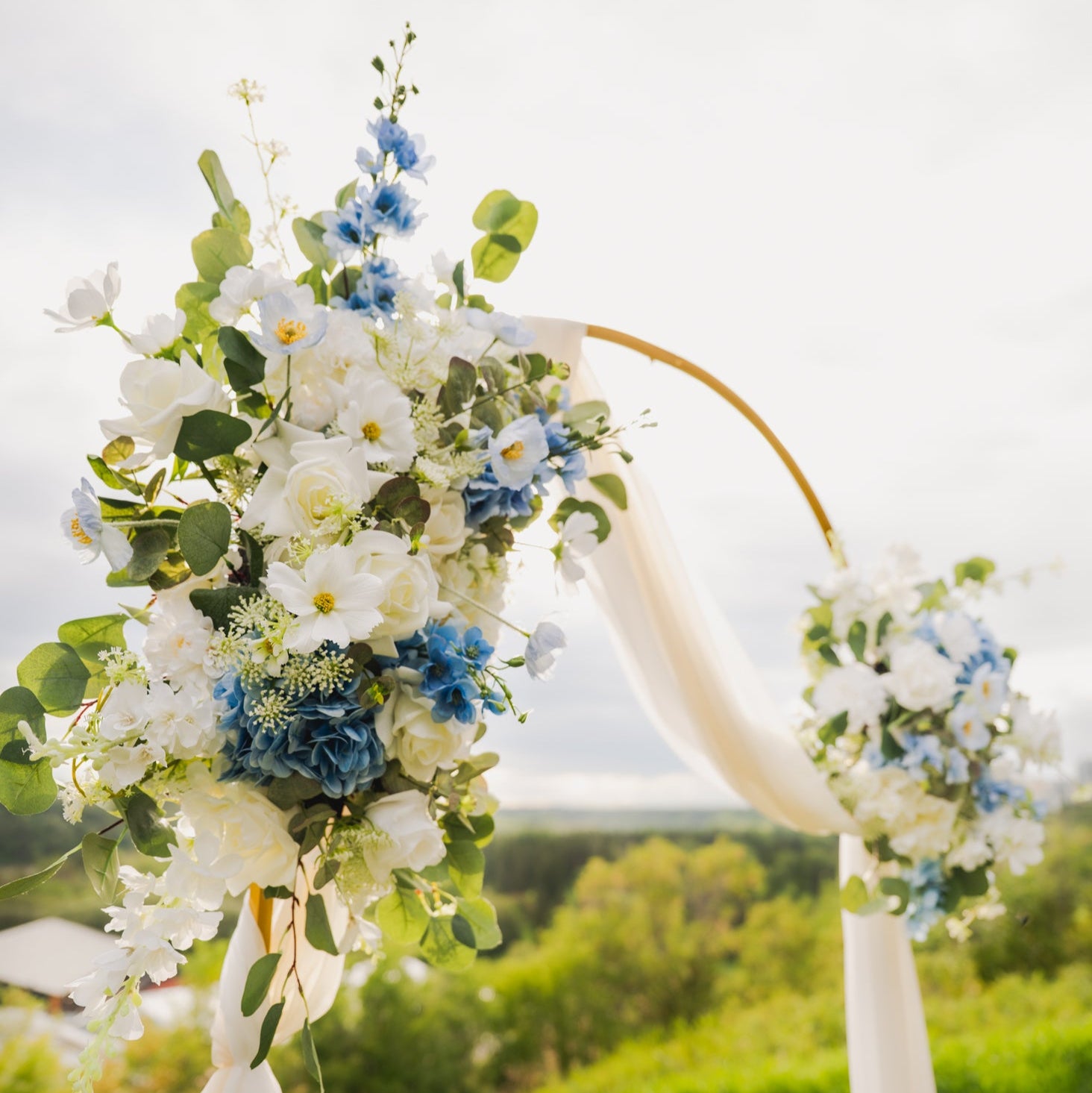 Ocean Breeze floral arch with white and blue flowers in an outdoor setting.
