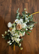 Floral arrangement with white, blush and brown accents with green foliage on a wooden background