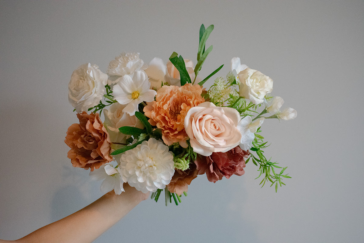 Bouquet of faux flowers held against a plain background