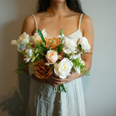 Woman holding a silk and real touch bridal bouquet against a neutral background