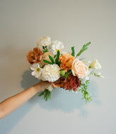 Bouquet of artificial flowers held by a person against a plain background