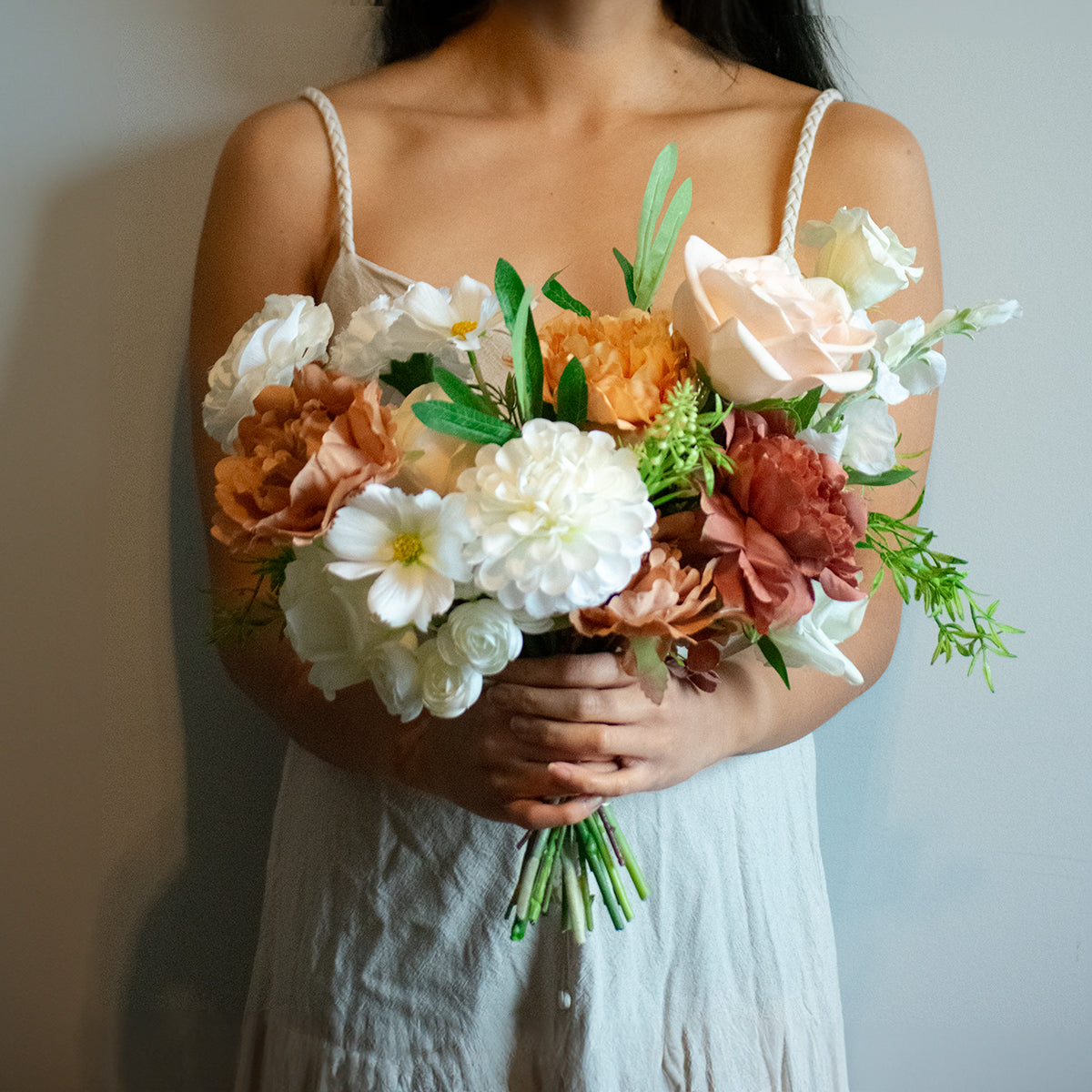 Woman holding a bouquet of artificial flowers against a neutral background