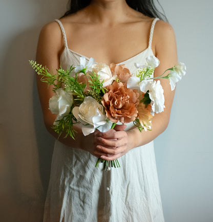 Person holding a bouquet of artificial flowers against a neutral background