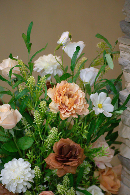 Bouquet of silk flowers up close with greenery against a neutral background