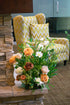 Floral arrangement on a stone surface with a yellow chevron-patterned chair in the background.