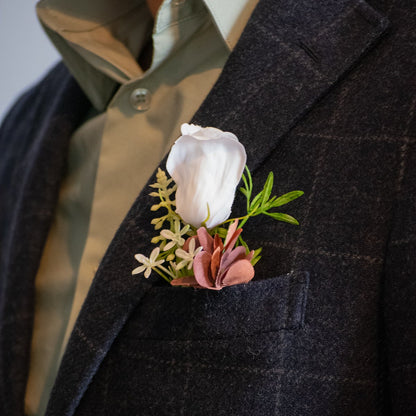 Real touch and silk groomsmen boutonniere on a dark suit jacket with a light shirt.
