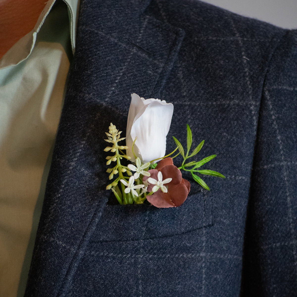 Faux floral boutonniere on a dark blue checkered suit jacket