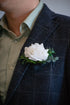 White real touch rose boutonniere on a dark suit jacket